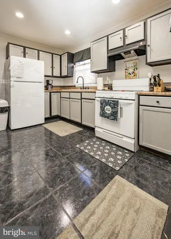 a kitchen with stainless steel appliances granite countertop a sink a stove a refrigerator and white cabinets