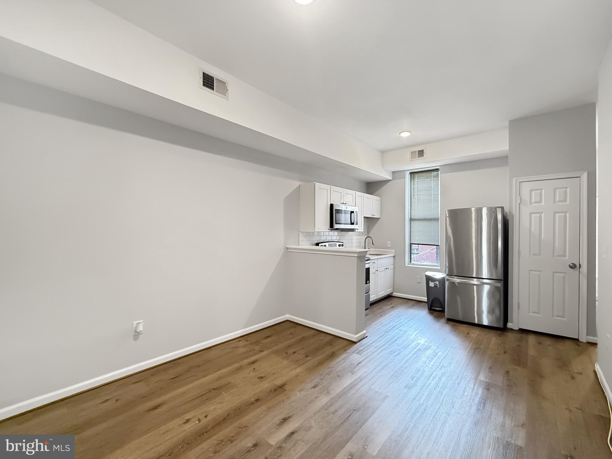 135 East North Avenue, Unit 2 Baltimore, MD 21202 - Photo 24 of 29 a view of a kitchen with a refrigerator and wooden floor