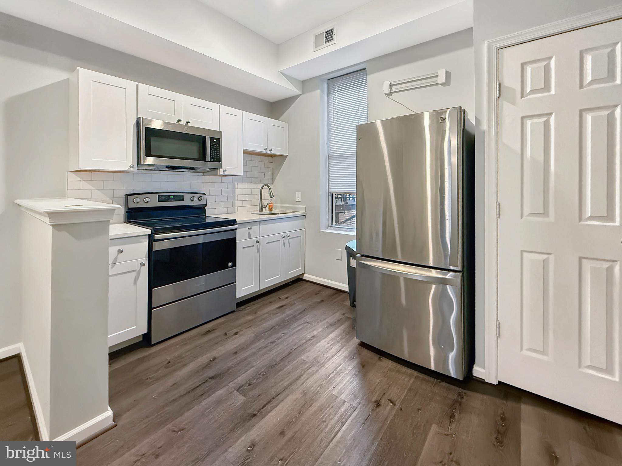 135 East North Avenue, Unit 2 Baltimore, MD 21202 - Photo 4 of 29 a kitchen with stainless steel appliances a refrigerator a stove top oven a sink and cabinets
