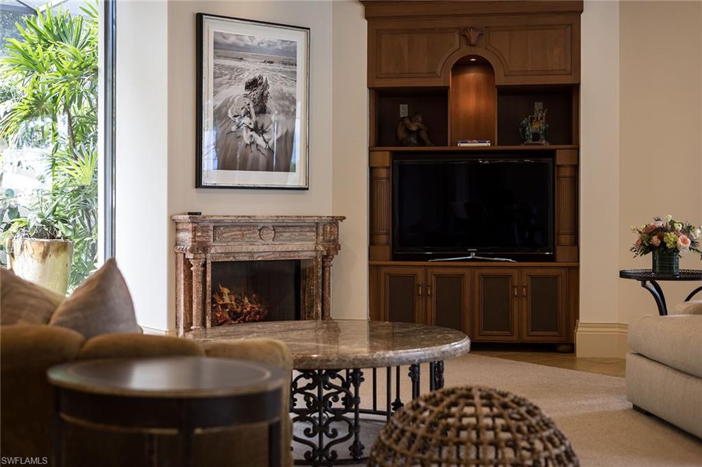 15167 Brolio Lane Naples, FL 34110 - Photo 35 of 50 a living room with furniture a flat screen tv and a fireplace