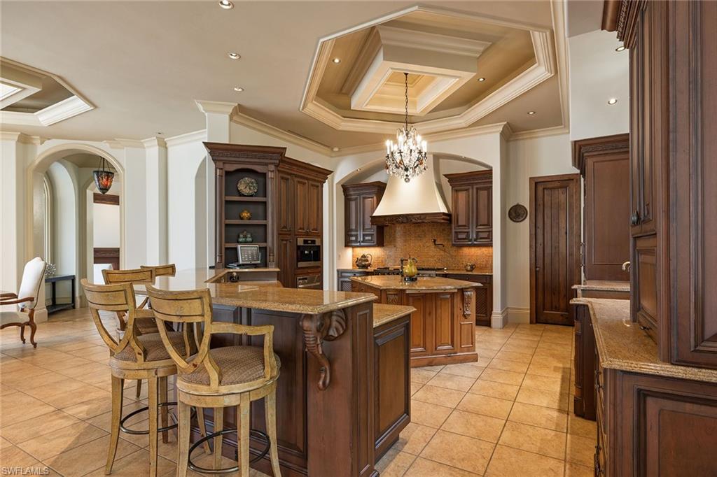 15167 Brolio Lane Naples, FL 34110 - Photo 7 of 50 a kitchen with stainless steel appliances a stove center island a dining table and chairs