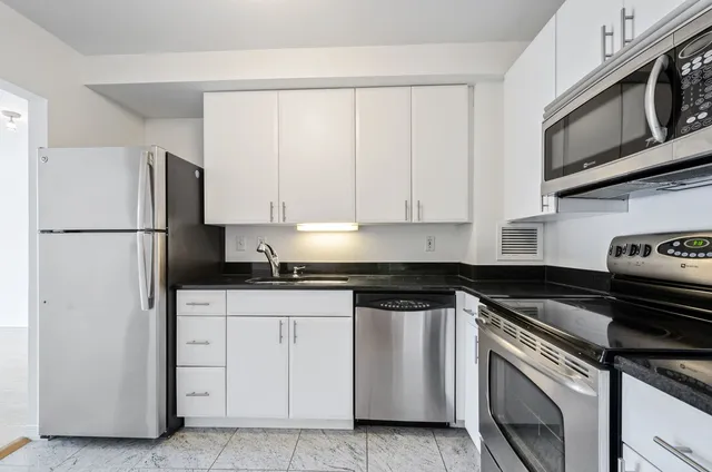 a kitchen with white cabinets and black appliances