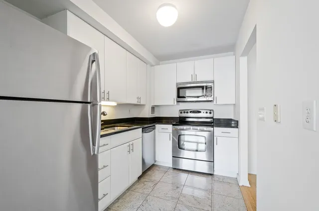 a kitchen with stainless steel appliances granite countertop a refrigerator sink and stove