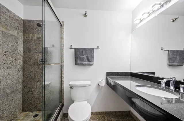 a bathroom with a granite countertop sink toilet a mirror and shower