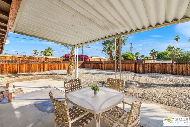 a patio with a table and chairs and potted plants