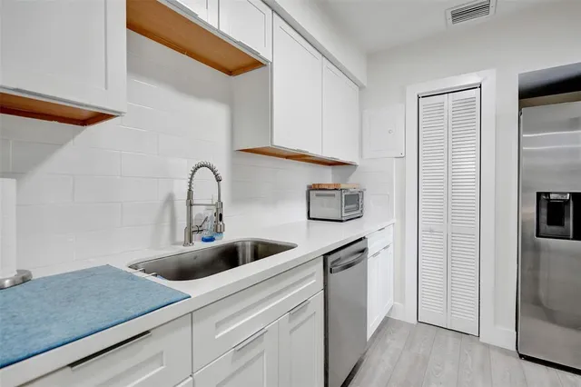 a kitchen with white cabinets and sink