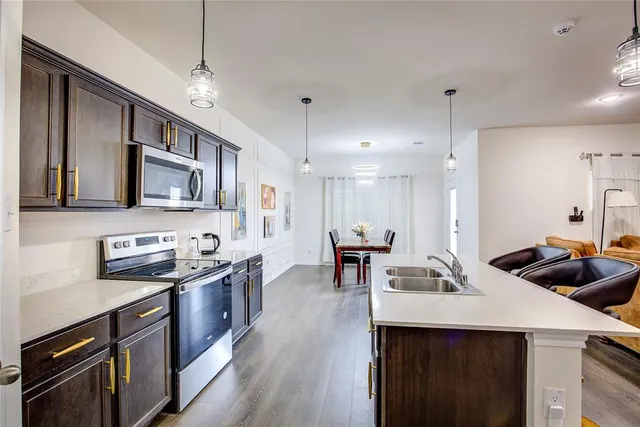 a kitchen with stainless steel appliances kitchen island granite countertop a sink a stove and a wooden floors