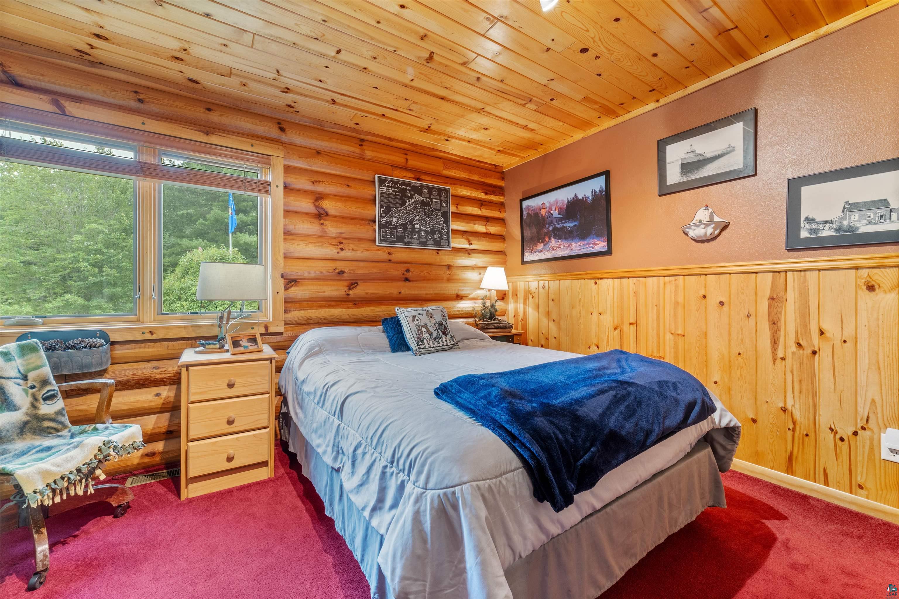 11911 East Rowe Road Lake Nebagamon, WI 54849 - Photo 47 of 61 Rustic bedroom featuring log walls, wood-paneled wainscoting, and wood-finish ceiling