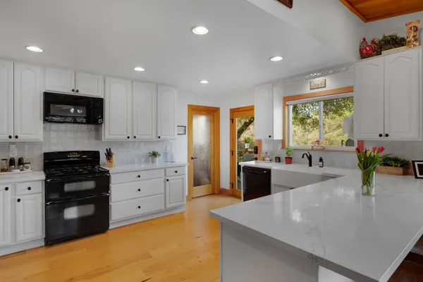 a kitchen with cabinets a sink appliances and a large window