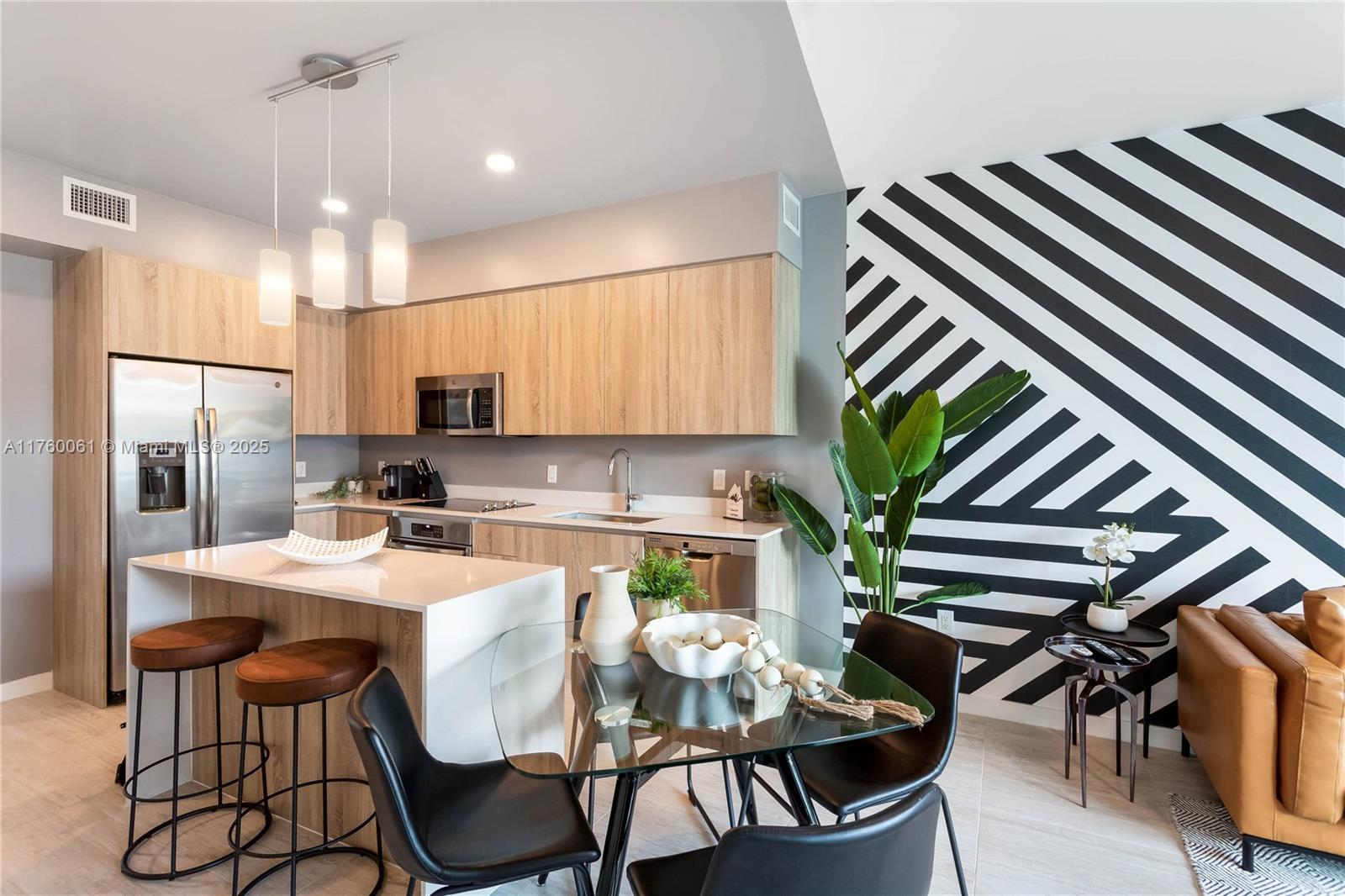 3900 Biscayne Boulevard, Unit S314 Miami, FL 33137 - Photo 5 of 15 a kitchen with stainless steel appliances kitchen island granite countertop a dining table chairs and white cabinets