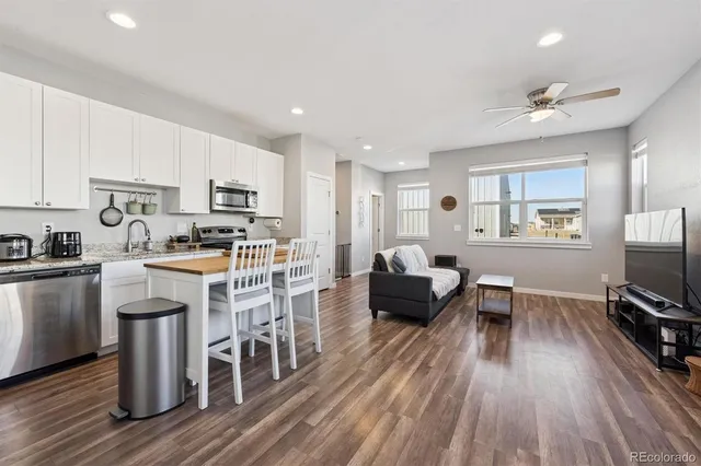 a living room with stainless steel appliances furniture and a wooden floor