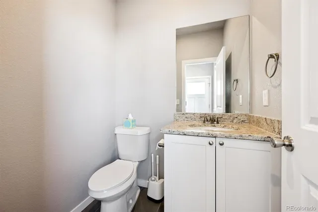 a bathroom with a granite countertop toilet sink and mirror
