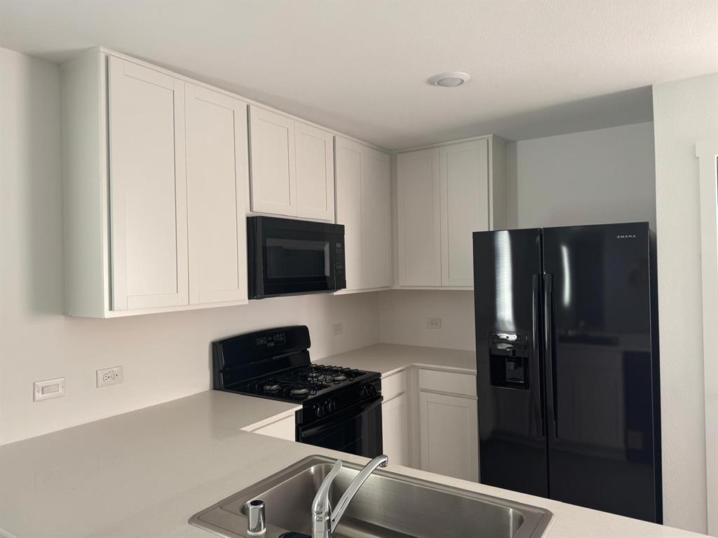 7505 Fenton Parkway Pilot Point, TX 76258 - Photo 12 of 30 a kitchen with a refrigerator stove and cabinets