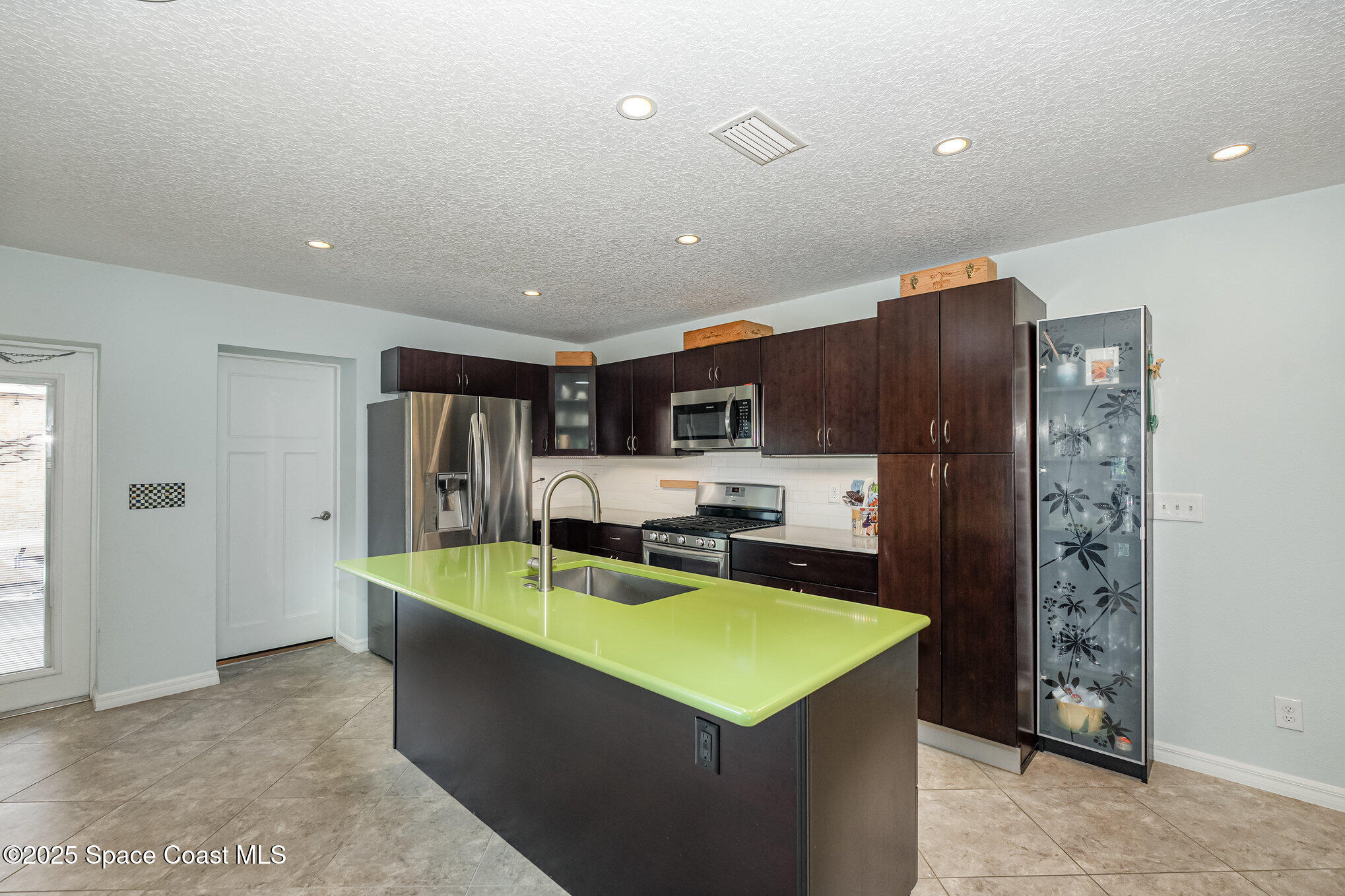 6203 Ridgewood Avenue Cocoa Beach, FL 32931 - Photo 9 of 37 a kitchen with stainless steel appliances kitchen island granite countertop a refrigerator and a stove top oven