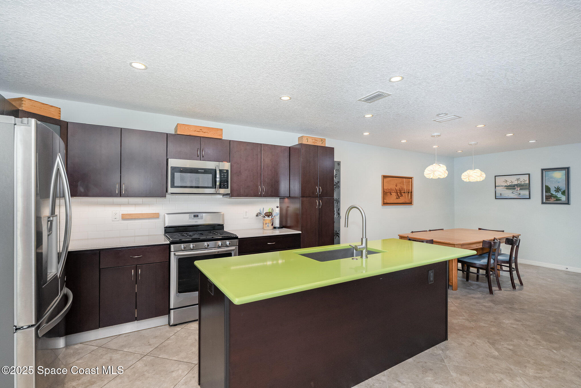 6203 Ridgewood Avenue Cocoa Beach, FL 32931 - Photo 10 of 37 a kitchen with stainless steel appliances kitchen island granite countertop a refrigerator and a stove top oven