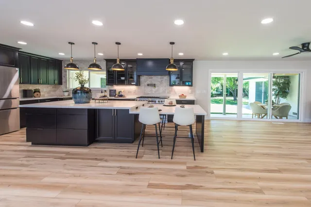 a kitchen with stainless steel appliances granite countertop a stove top oven a sink dishwasher and chairs