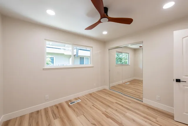 a view of an empty room with wooden floor and a window