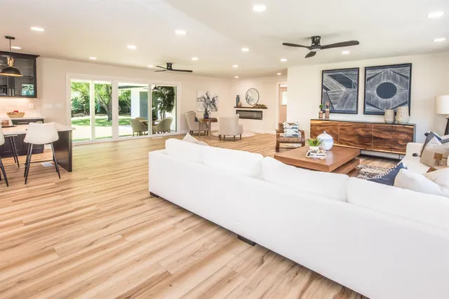 a large living room with stainless steel appliances kitchen island granite countertop a large kitchen island a stove a sink a dining table and chairs with wooden floor