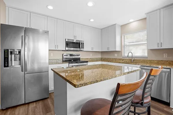 a kitchen with stainless steel appliances granite countertop a refrigerator a stove a sink a dining table and chairs