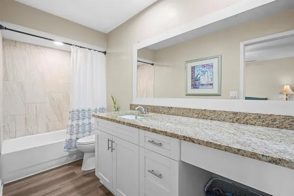 a bathroom with a granite countertop sink a mirror a vanity and a bathtub