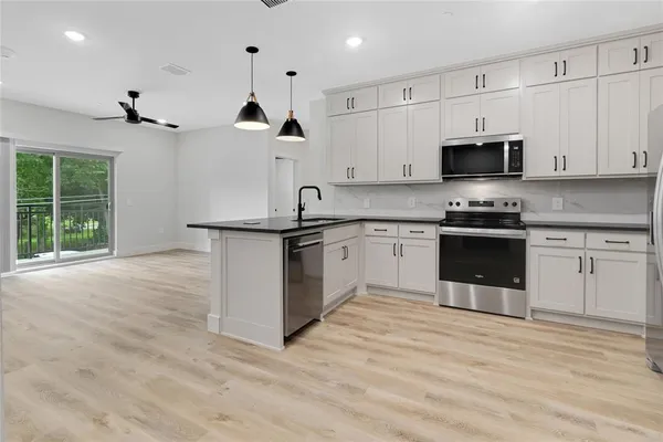 a kitchen with stainless steel appliances granite countertop a stove a sink and a microwave