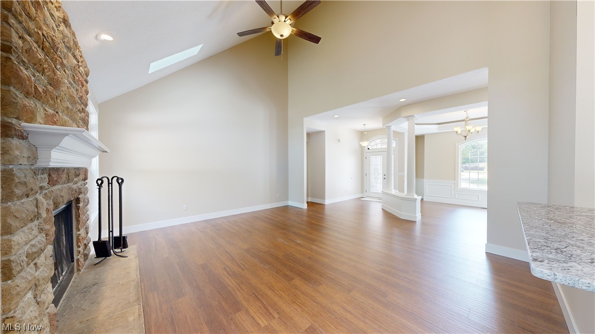 8325 Munson Road Mentor, OH 44060 - Photo 17 of 35 Hardwood floored living room with ceiling fan, vaulted ceiling with skylight, a high ceiling, and a fireplace