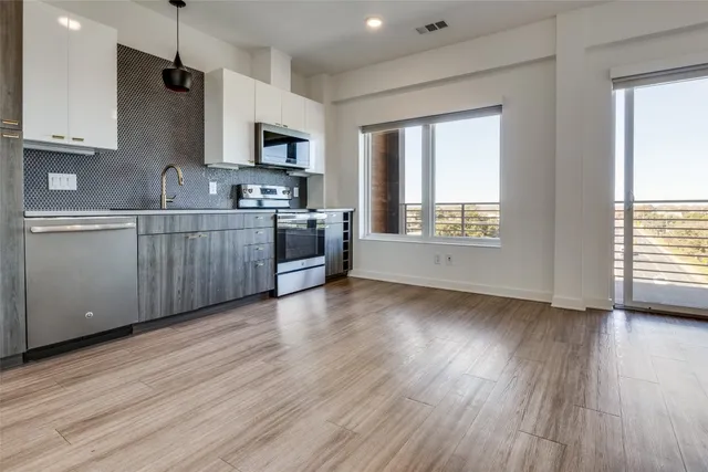 a kitchen with stainless steel appliances granite countertop a stove a sink dishwasher a microwave oven and a wooden floor