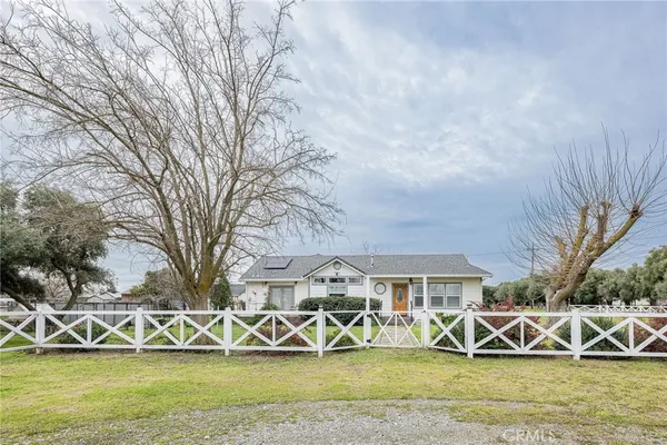 a view of a white house next to yard with large trees