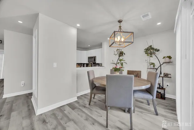 a dining room with wooden floor potted plants and a chandelier
