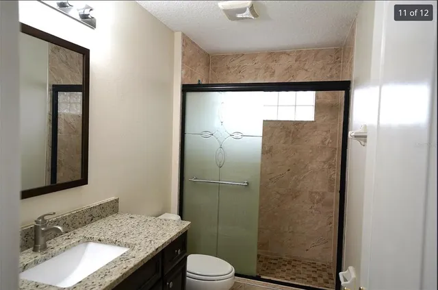 a bathroom with a granite countertop sink toilet and shower
