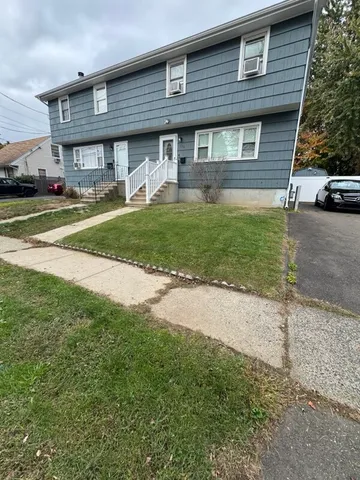 a front view of a house with a garden and trees