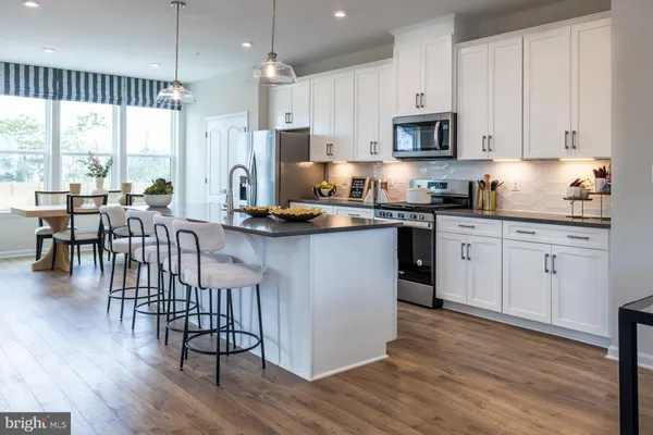 a kitchen with stainless steel appliances granite countertop a stove top oven a sink a dining table and chairs with wooden floor