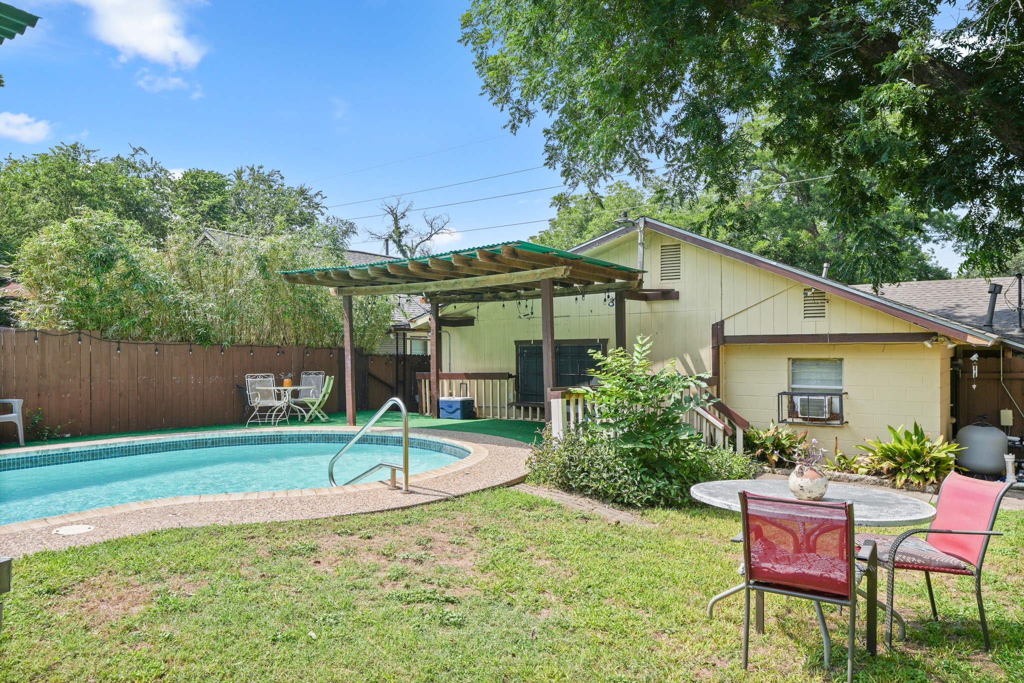 1908 Holly Street Austin, TX 78702 - Photo 20 of 22 An inviting backyard oasis offers a sparkling in-ground pool, covered patio, and lush surroundings for optimal outdoor living.