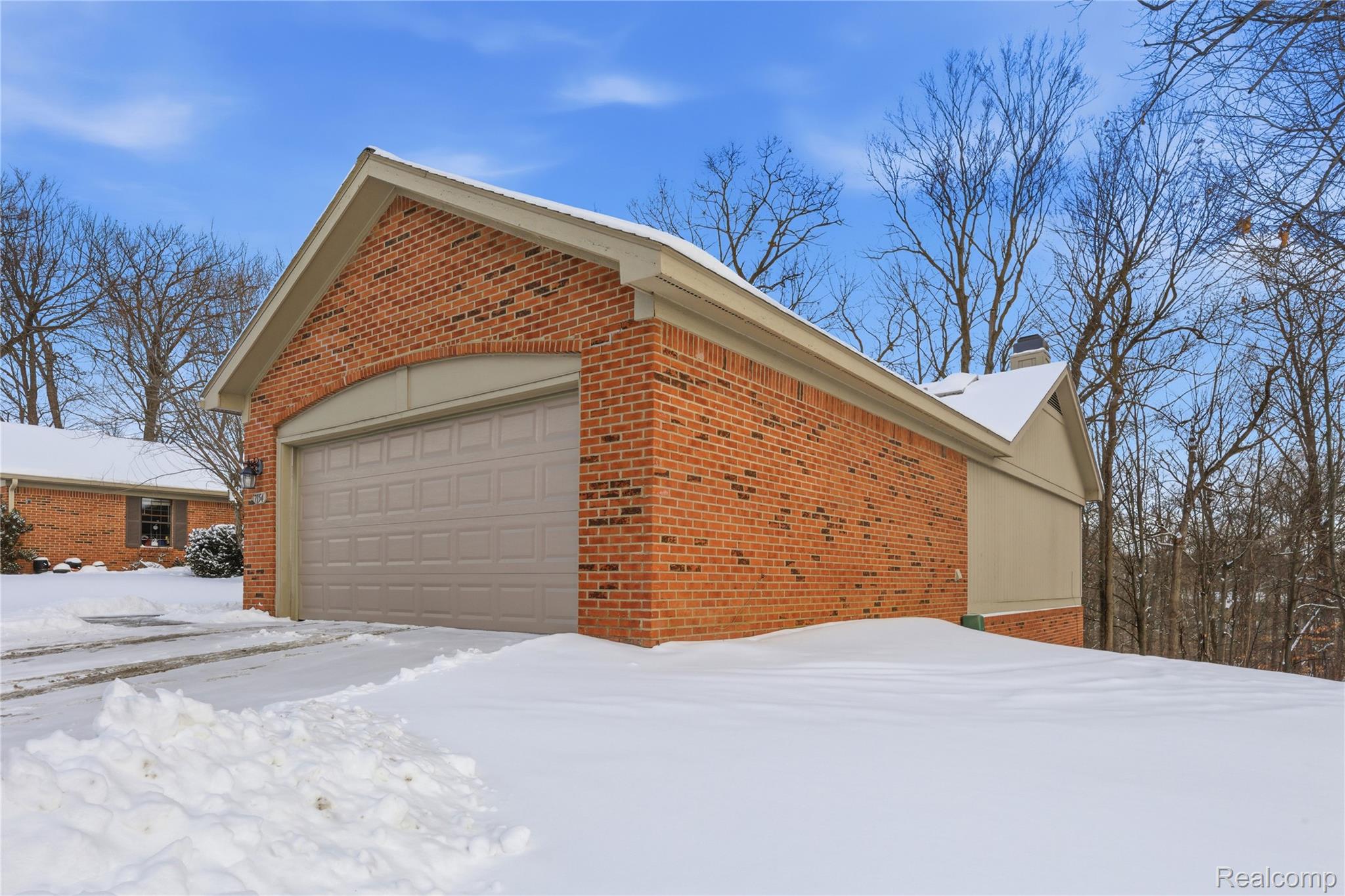 7154 Westchester Road West Bloomfield, MI 48322 - Photo 33 of 38 View of snow covered exterior featuring brick siding, a chimney, a garage, and an outbuilding