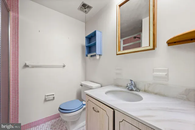 a bathroom with a granite countertop toilet sink and mirror