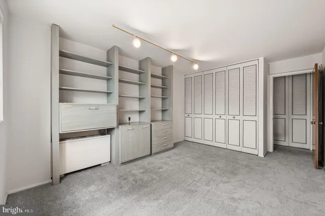 a view of an empty room with cabinet and mirrors