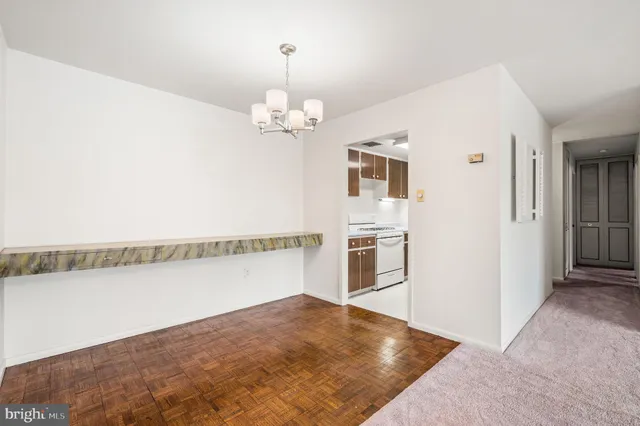 a view of a livingroom with a chandelier fan and kitchen view