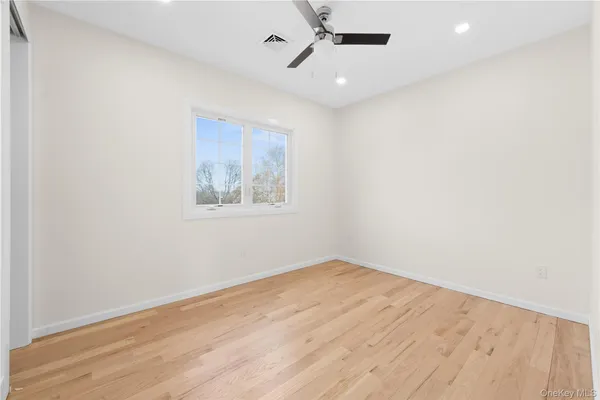 an empty room with wooden floor ceiling fan and windows