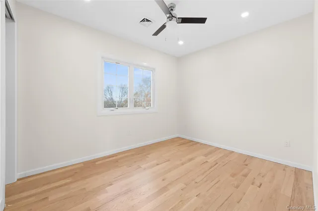 an empty room with wooden floor ceiling fan and windows
