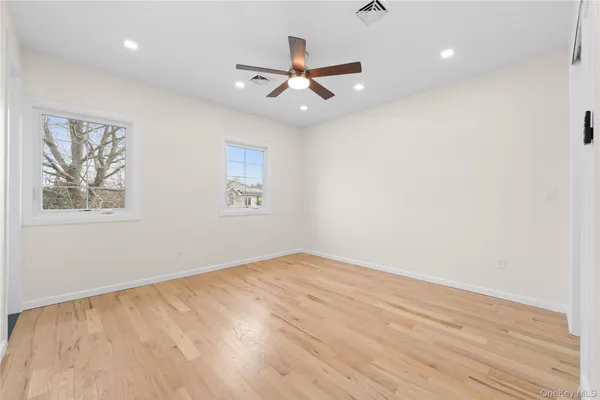 an empty room with wooden floor ceiling fan and window