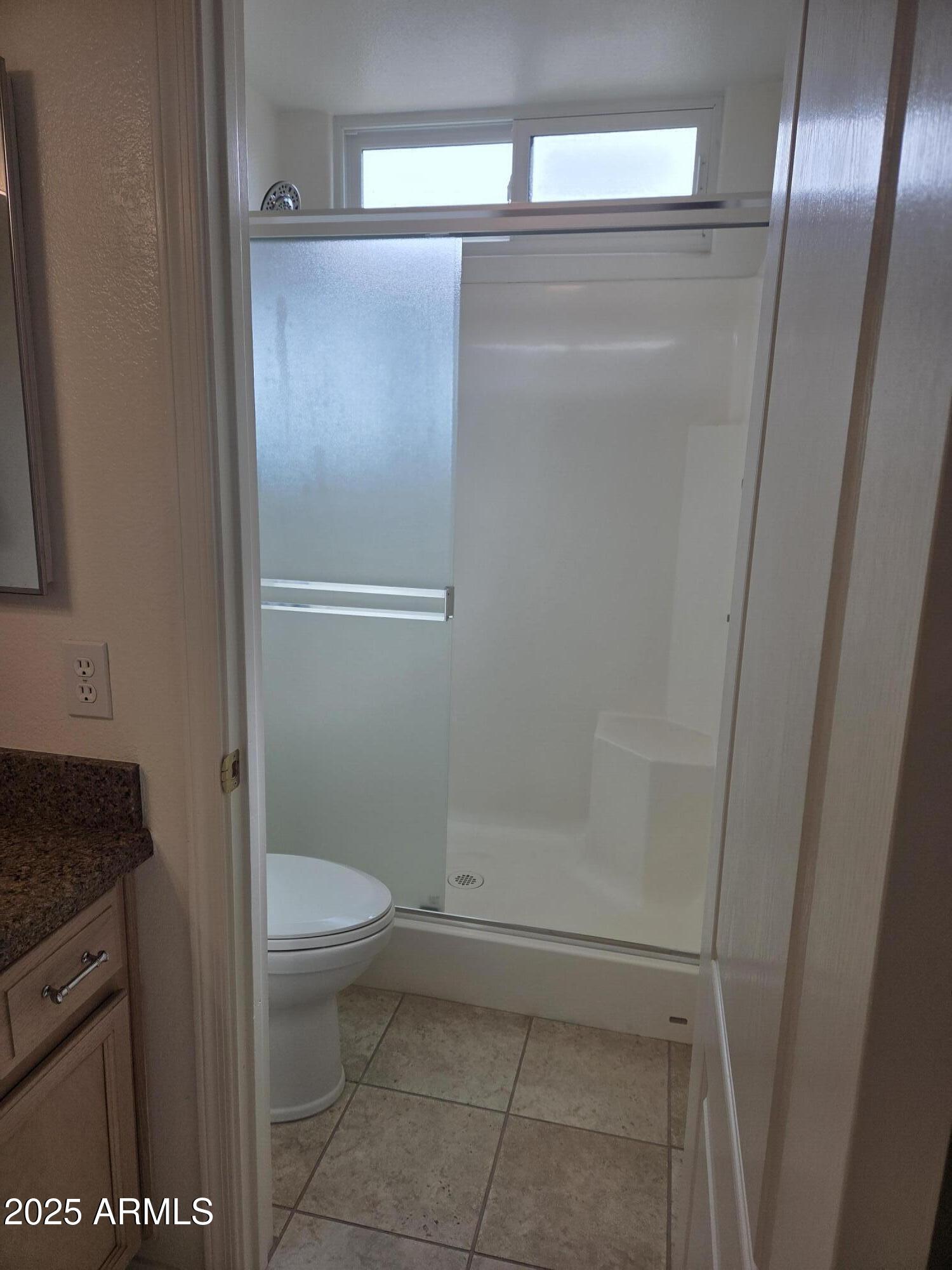 9151 West Greenway Road, Unit 182 Peoria, AZ 85381 - Photo 8 of 19 a bathroom with a granite countertop toilet and a shower