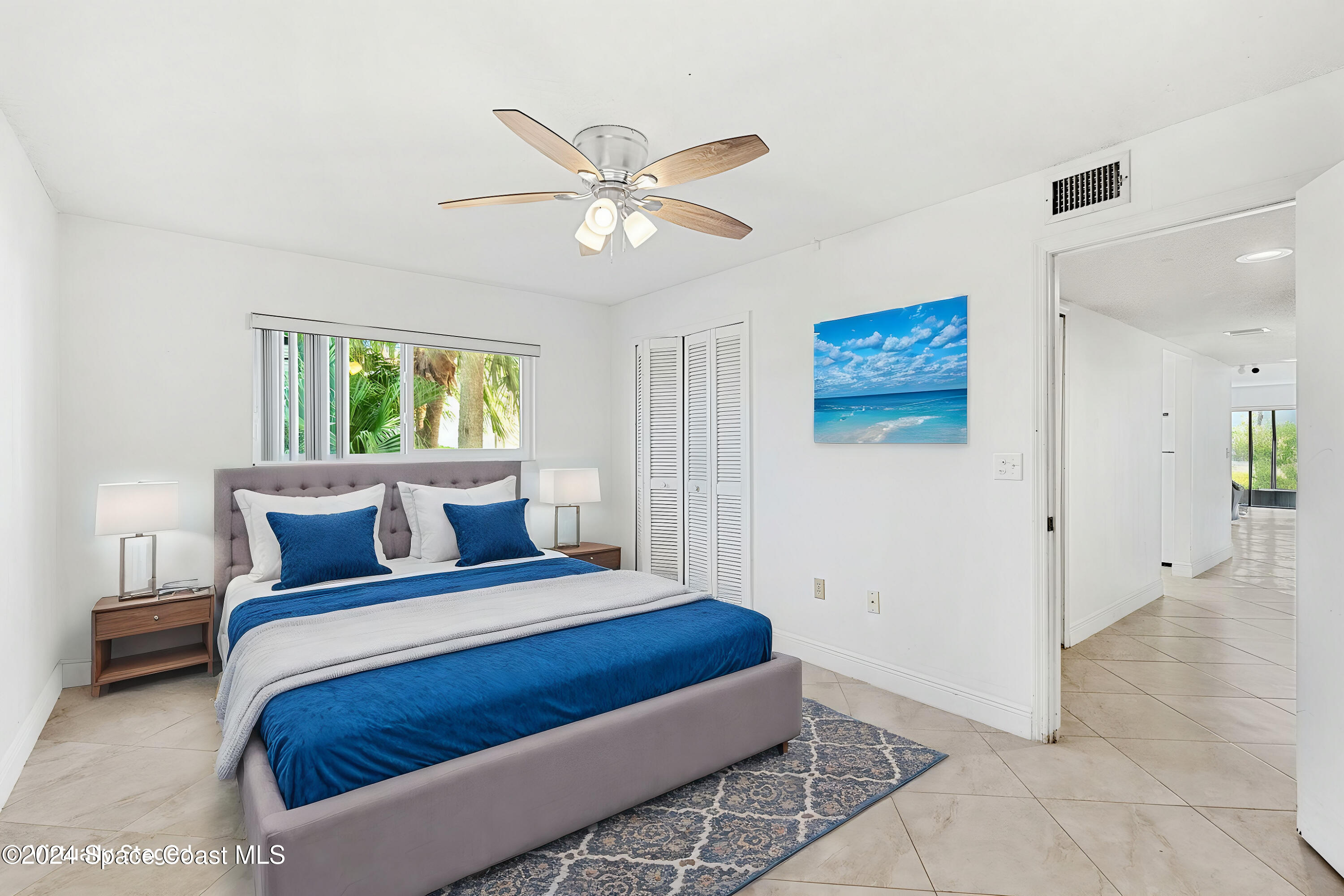 5807 North Atlantic Avenue, Unit 411 Cape Canaveral, FL 32920 - Photo 11 of 31 a bedroom with a large bed and a chandelier