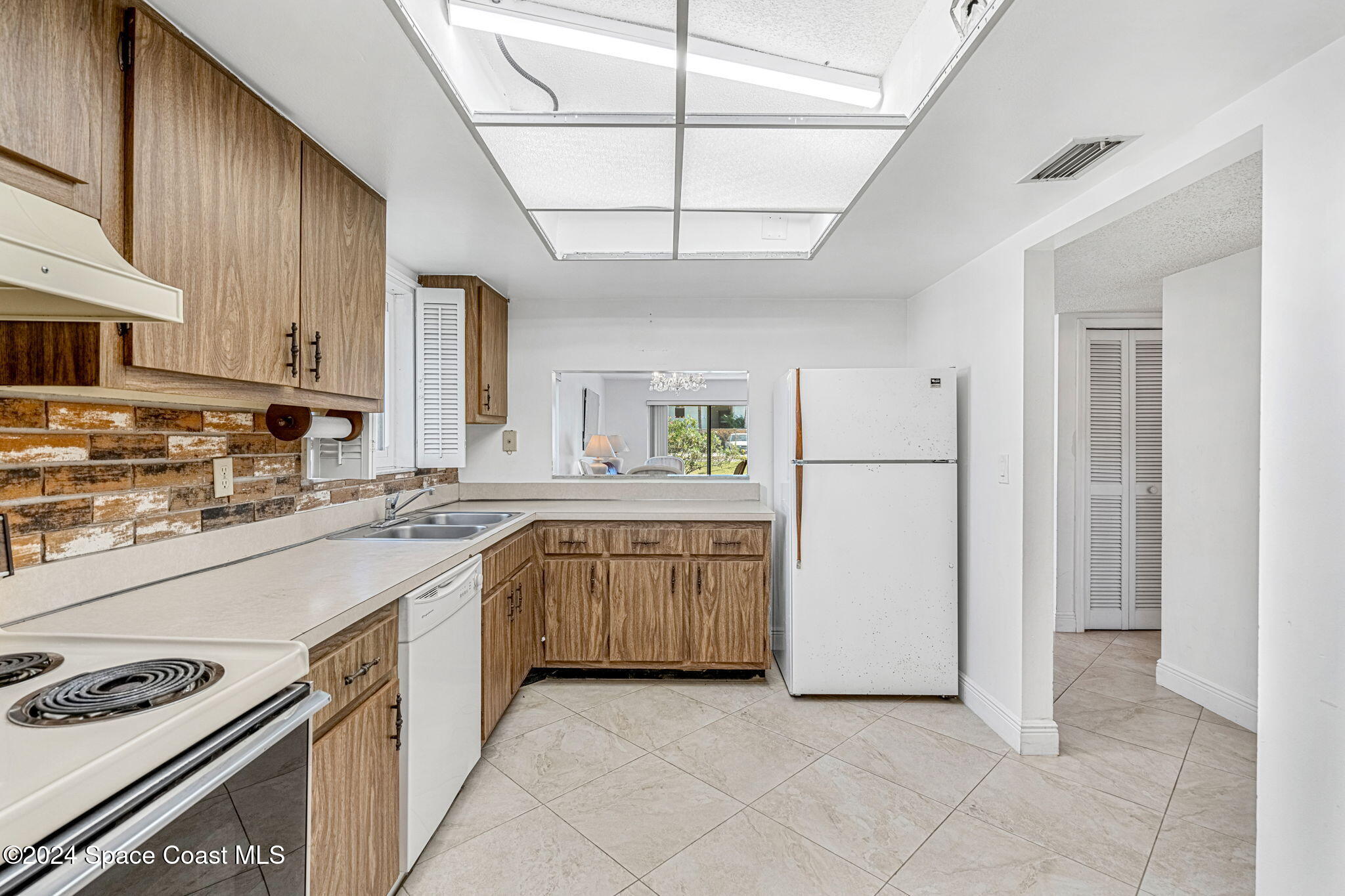 5807 North Atlantic Avenue, Unit 411 Cape Canaveral, FL 32920 - Photo 7 of 31 a kitchen with granite countertop a sink stove a refrigerator and white cabinets with wooden floor