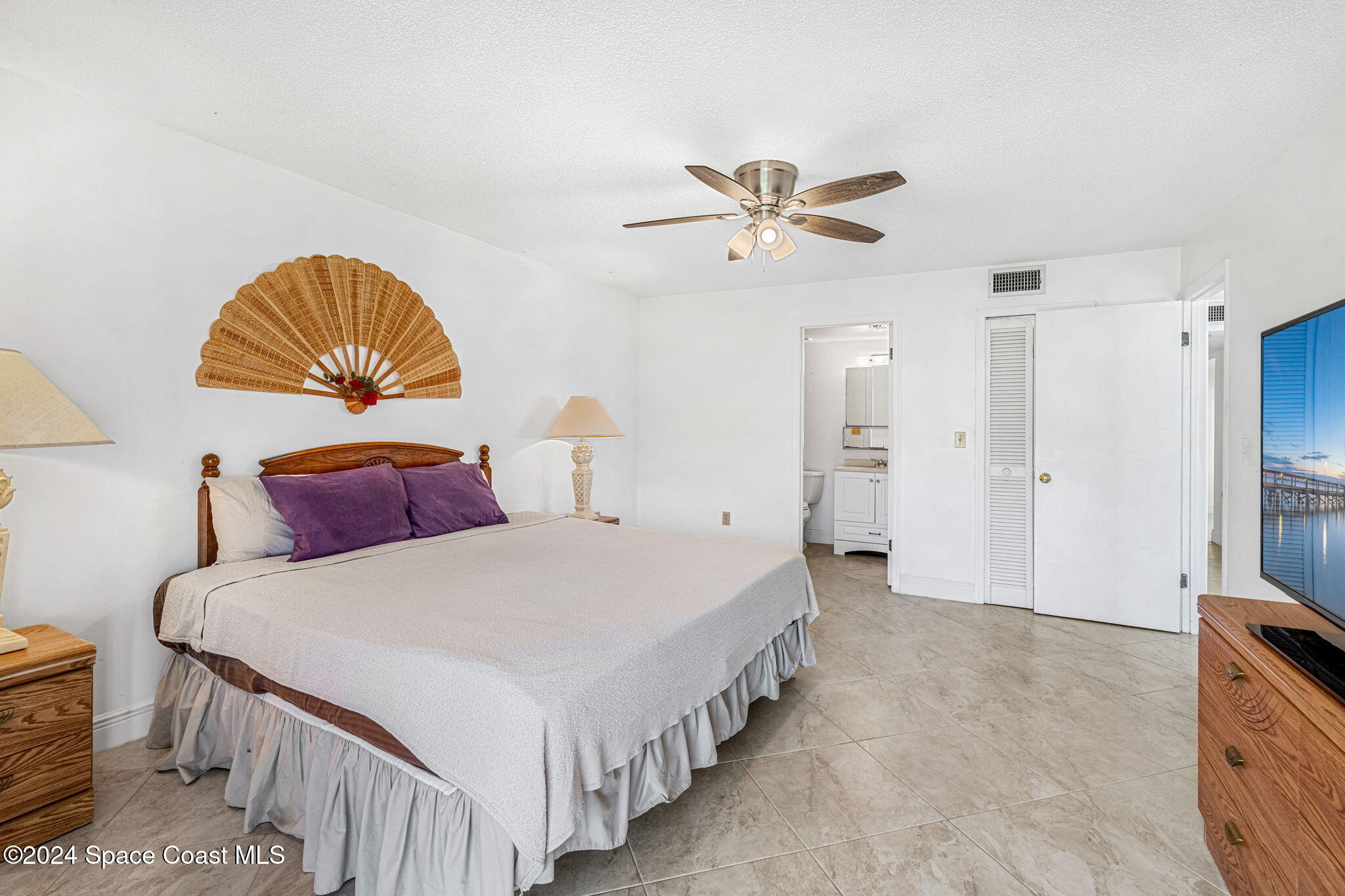 5807 North Atlantic Avenue, Unit 411 Cape Canaveral, FL 32920 - Photo 9 of 31 a bedroom with bed and a chandelier