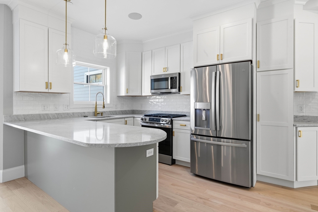 51 West Main Street, Unit 6R Georgetown, MA 01833 - Photo 10 of 40 a kitchen with kitchen island a sink stainless steel appliances and wooden cabinets