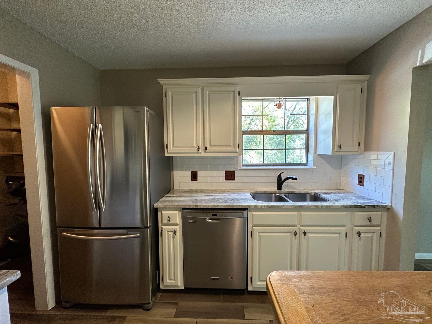 4831 East Olive Road, Unit 4D Pensacola, FL 32514 - Photo 6 of 17 a kitchen with stainless steel appliances granite countertop a refrigerator sink and cabinets