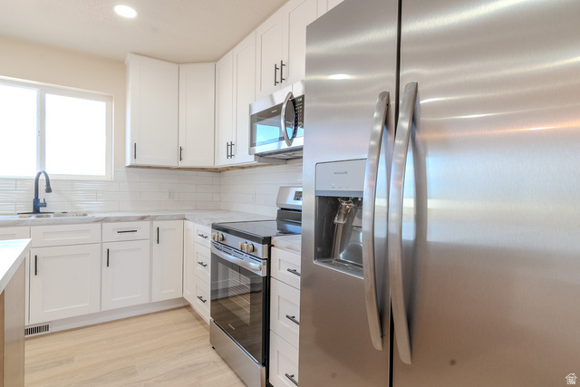 130 Pole Line Road, Unit 2 Roosevelt, UT 84066 - Photo 10 of 33 Kitchen featuring white cabinetry with dark hardware, a stainless steel refrigerator, and wood-finish flooring