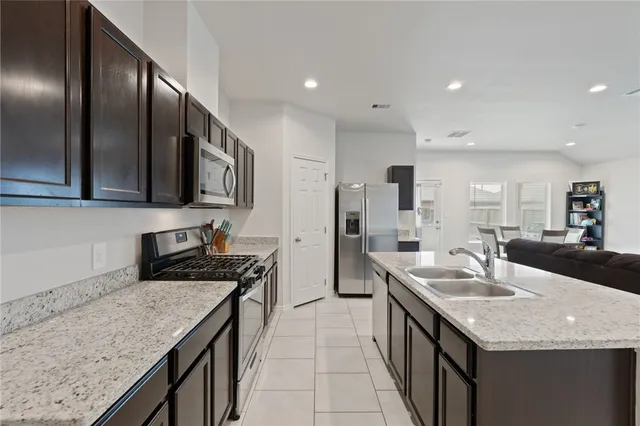 a kitchen with stainless steel appliances granite countertop a sink a stove and a refrigerator