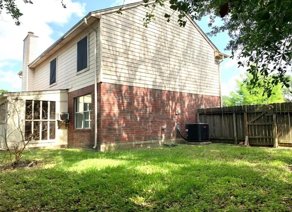 a view of backyard with large tree and wooden fence