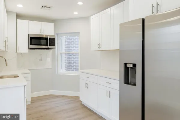 a kitchen with stainless steel appliances white cabinets and a refrigerator
